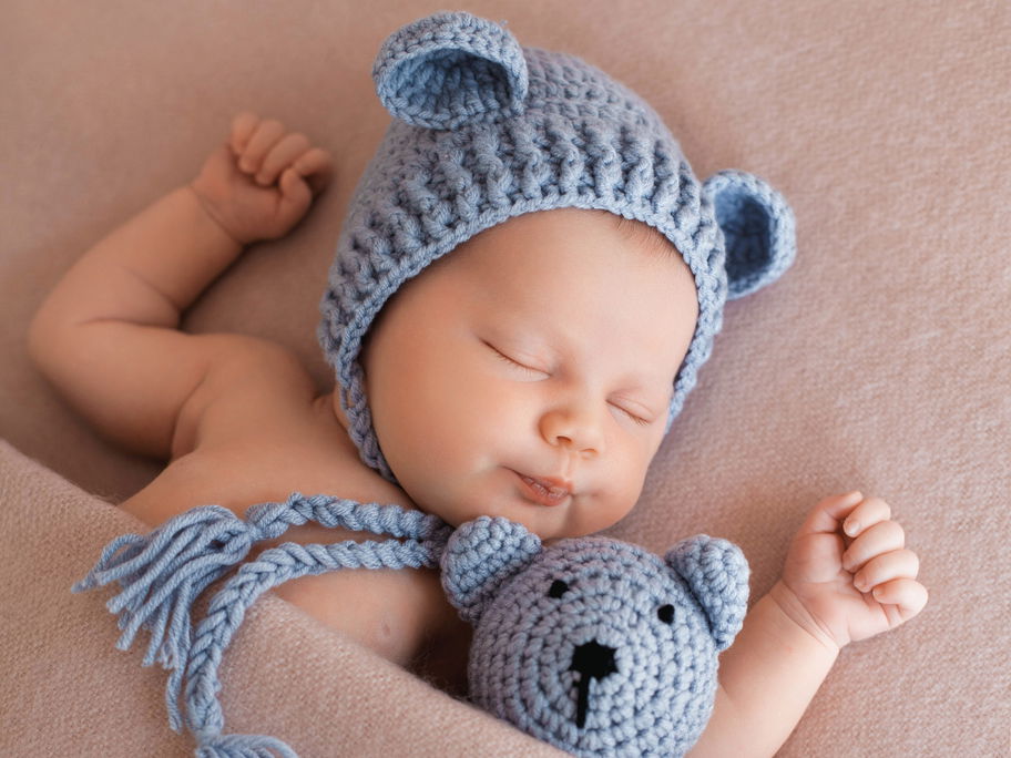 Kleiner Junge schläft mit seinem Teddy im Bett
