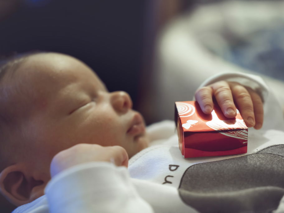 Baby hält Geschenk zur Geburt in der Hand