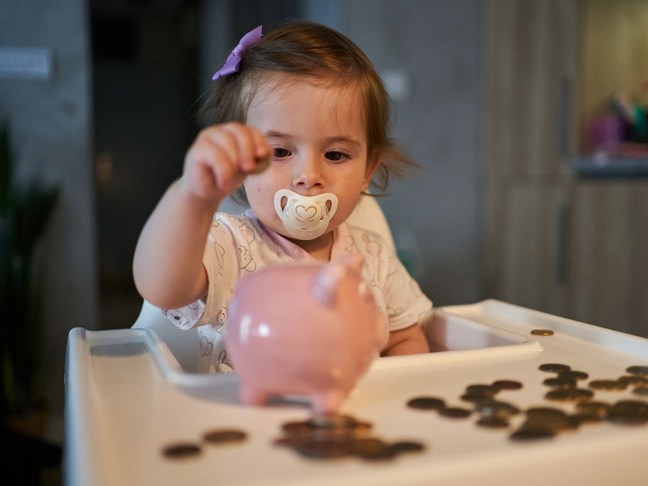 Kleinkind wirft Geld ins Sparschwein.