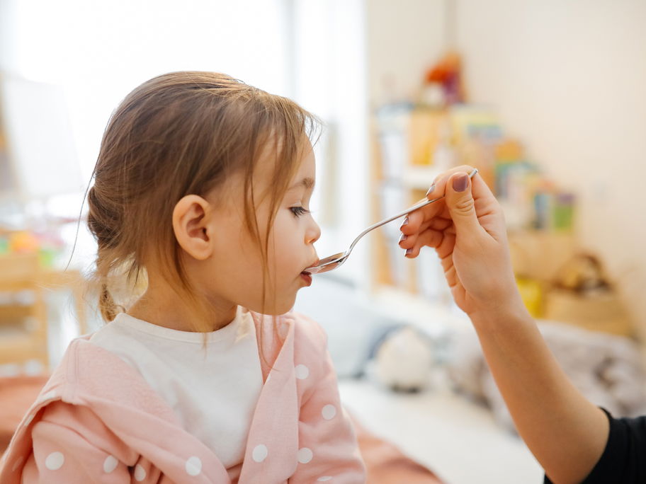 Mädchen bekommt einen Löffel mit Medizin