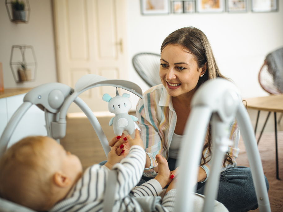 Mama schaukelt Baby in Babywippe
