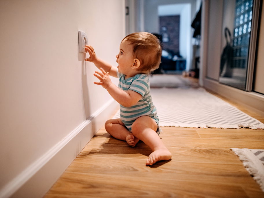 Baby fasst in die gesicherte Steckdose