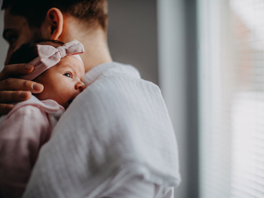 Papa hält neugeborene Tochter im Arm