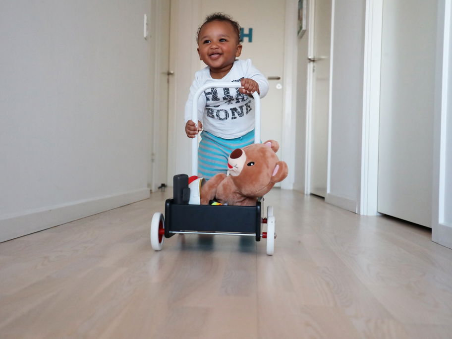 Kleiner Junge lernt laufen am Lauflernwagen
