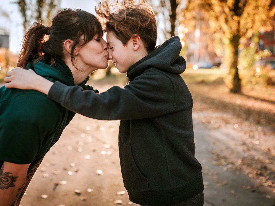 Eine Mutter küsst ihren Teenager-Jungen zärtlich auf die Nase.