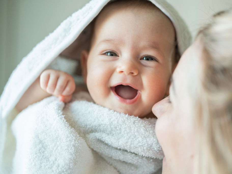 Lachendes Baby unter einem Handtuch.