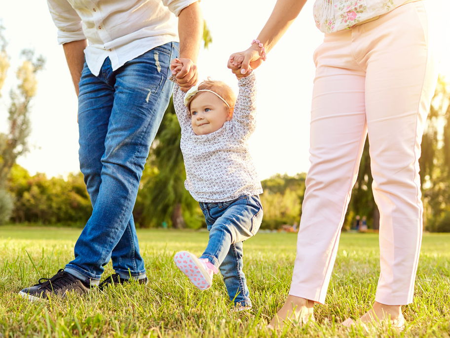 Baby übt das Laufen mit seinen Eltern