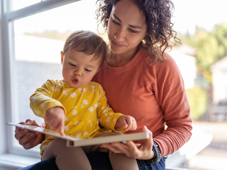 Mama und Kleinkind schauen sich ein Buch an