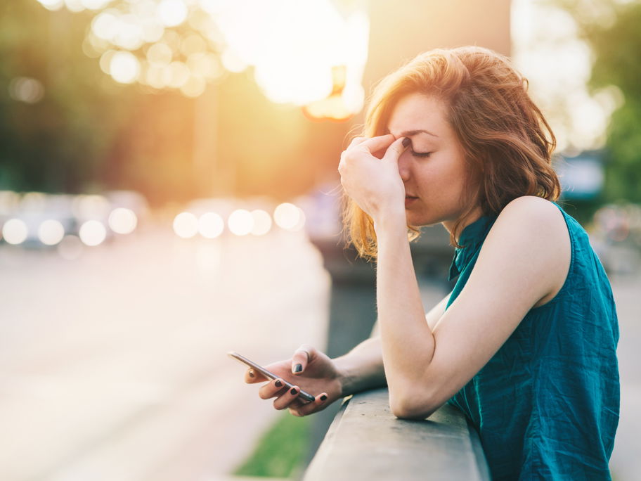 Frau gestresst mit Handy in der Hand