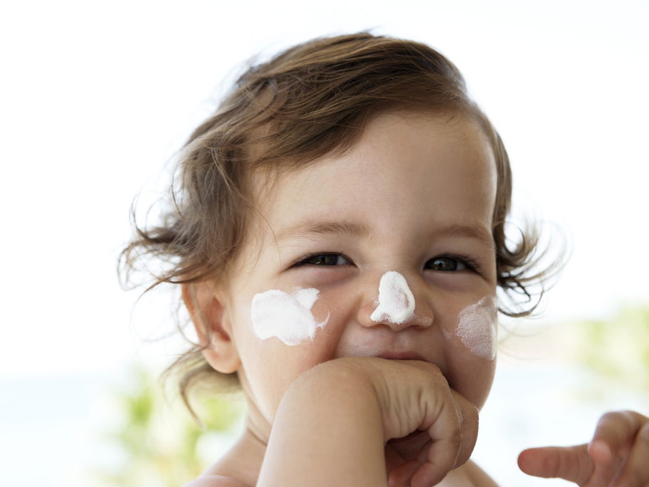 Kleines Kind mit Sonnencreme im Gesicht