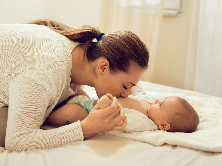 Mama kuschelt mit Baby beim Wickeln