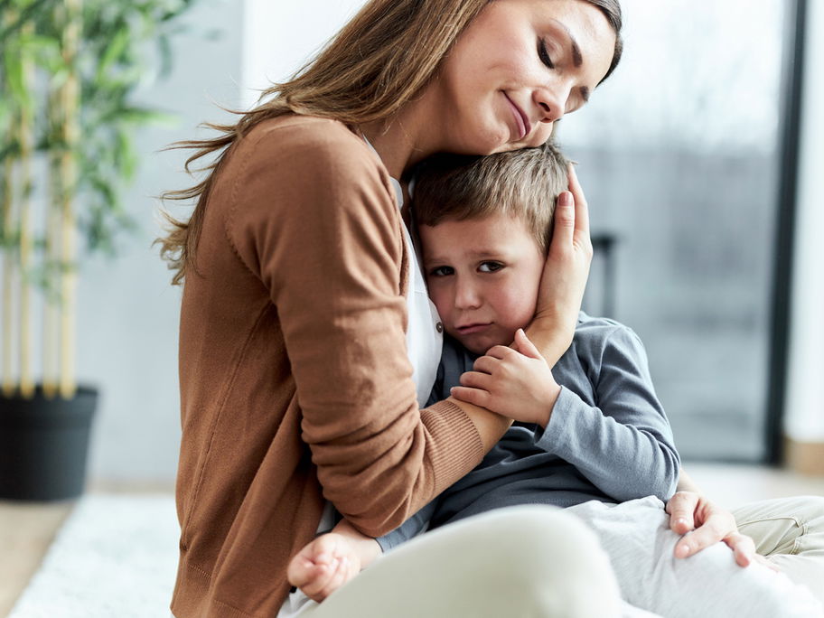 Liebevolle Mutter, die ihren traurigen Sohn zu Hause tröstet.