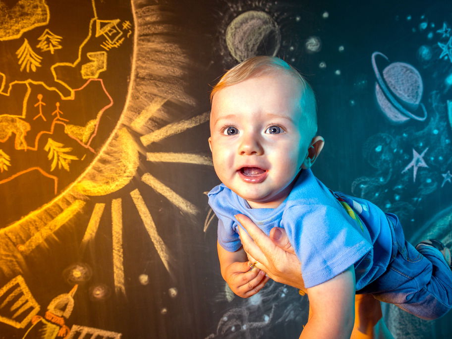 Baby schwebt auf den Händen der Eltern durch den "Weltraum"