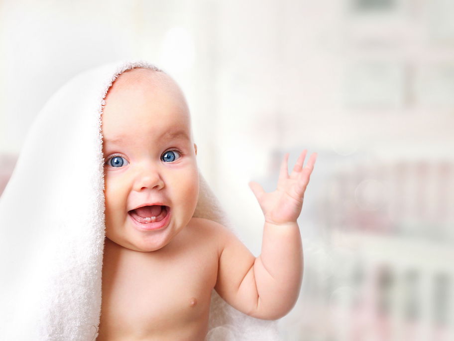 Lachendes Baby unter Handtuch.