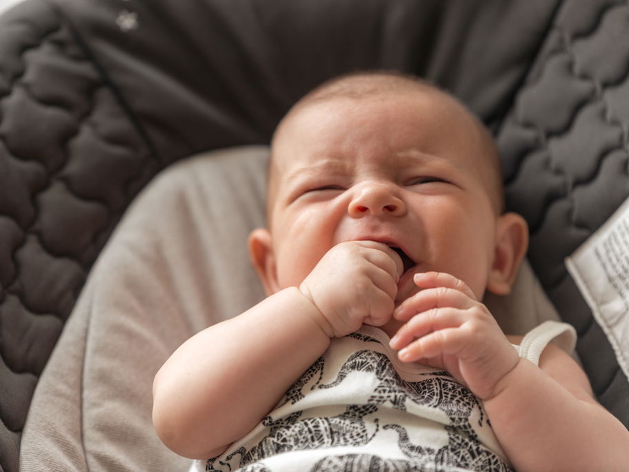 Quengeliges Baby kaut auf seiner Hand