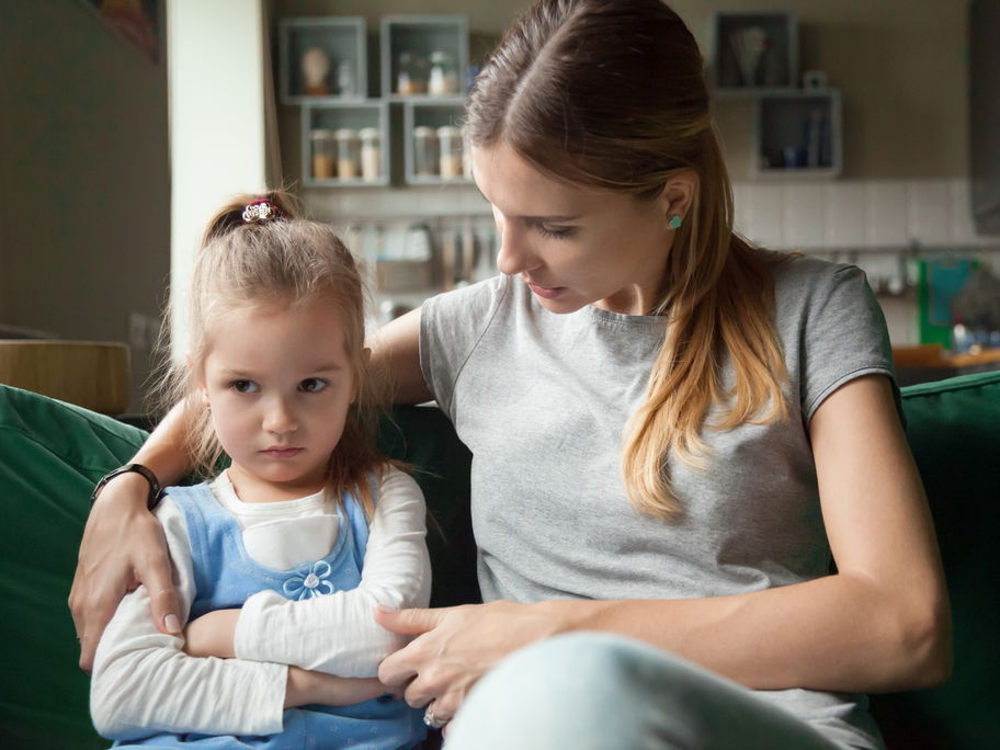 Junge Mutter spricht einfühlsam und liebevoll mit ihrer kleinen Tochter.