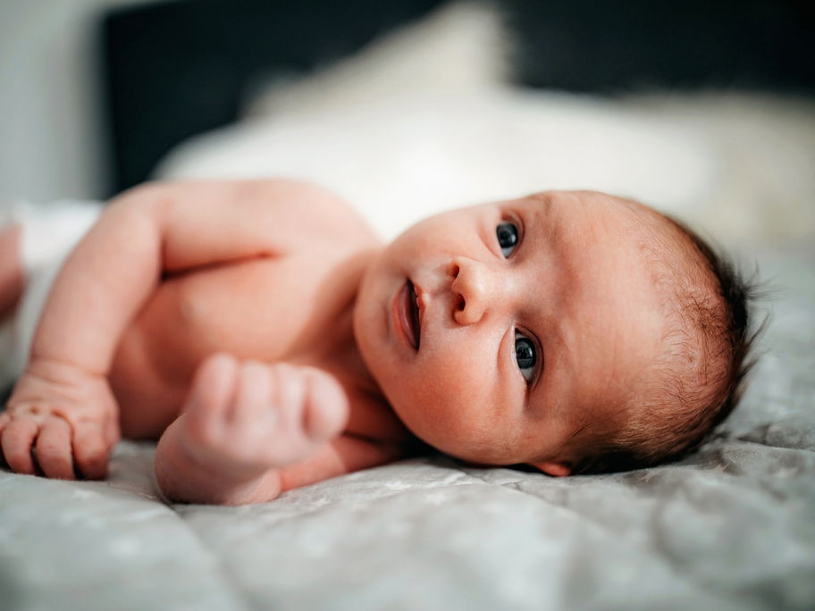 Neugeborenes Baby liegt auf einer Decke.