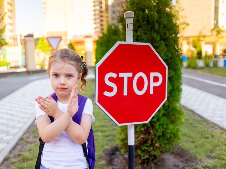 Grenzen ziehen: Kleines Schulmädchen sagt Nein an einem Stopp-Schild