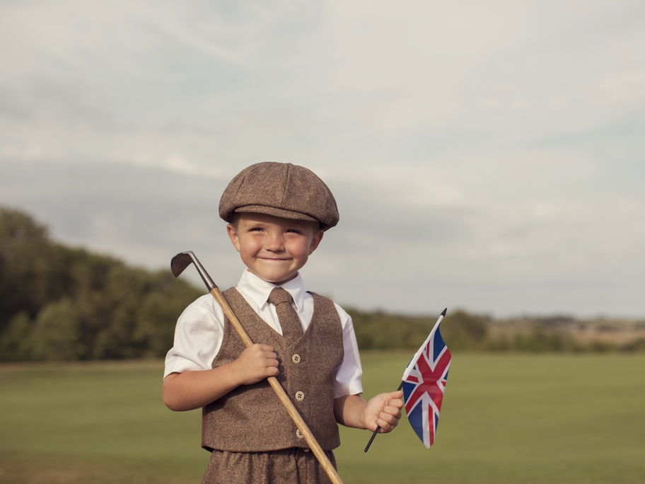 Englischer kleiner Junge in Vintage-Kleidung hält eine britische Flagge in der Hand