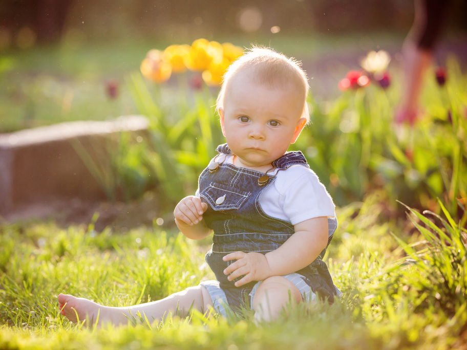 Ein kleiner Junge sitzt auf dem Gras und staunt.