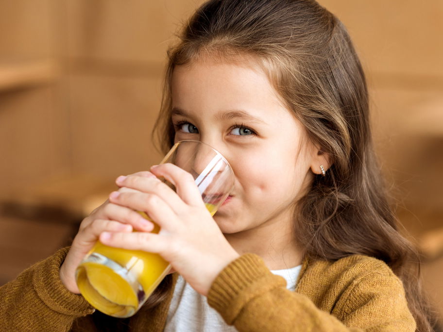 Lächelndes Mädchen trinkt ein Glas Orangensaft
