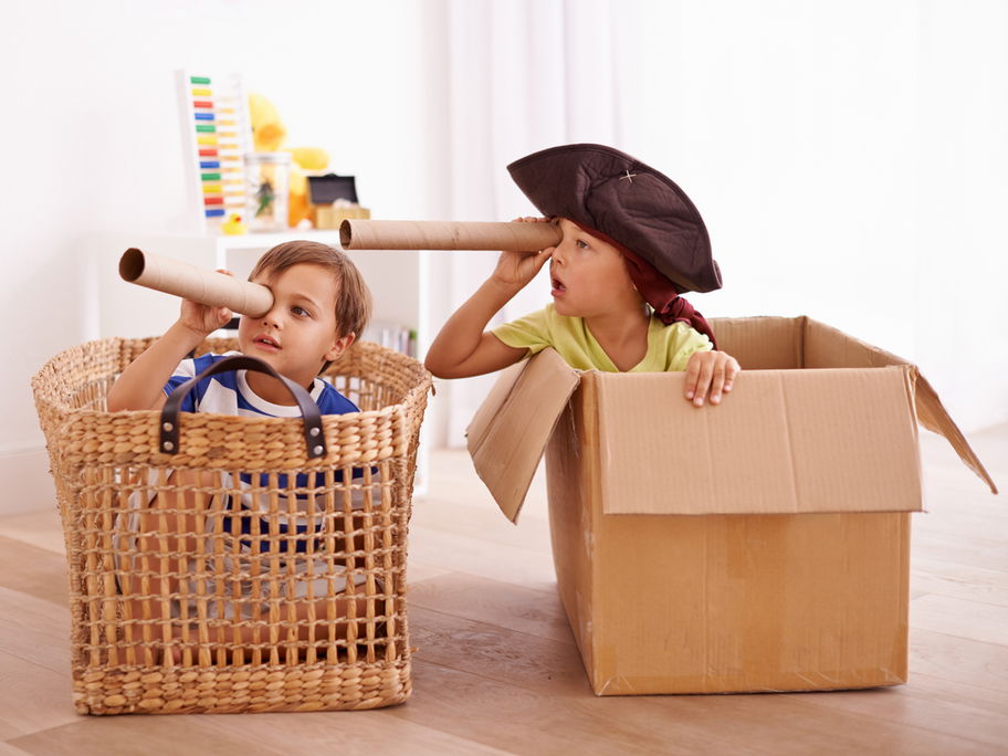Zwei Kinder spielen in Korb und Karton Piraten.