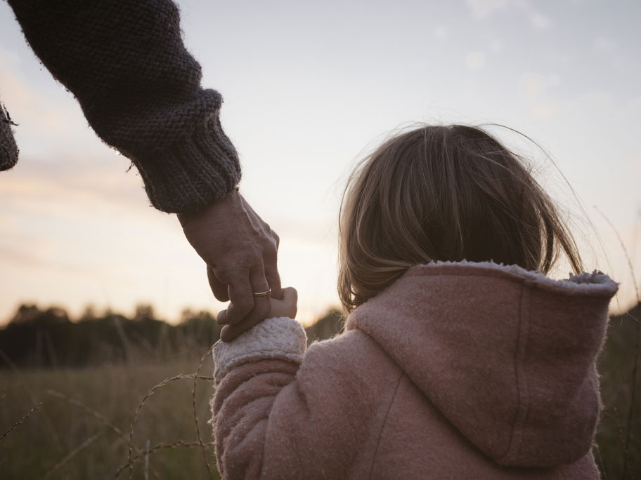 Vater hält die Hand seiner Tochter.