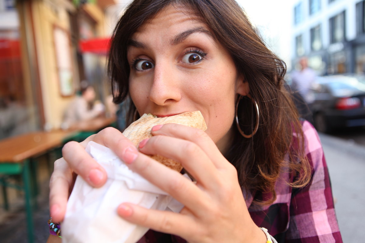 Eine schwangere Frau beißt genüsslich in einen Döner.