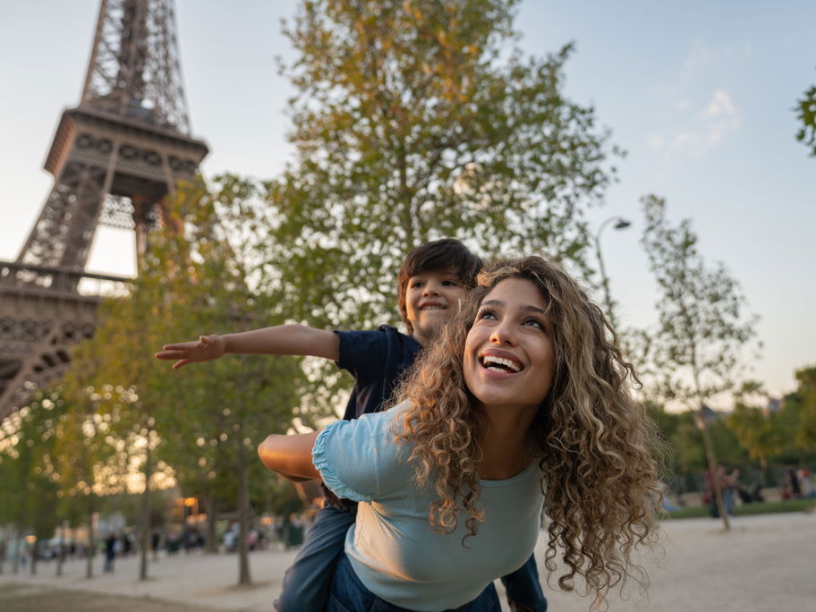 Eine Mutter und ihr Sohn spielen vor dem Eiffelturm in Paris, Frankreich.