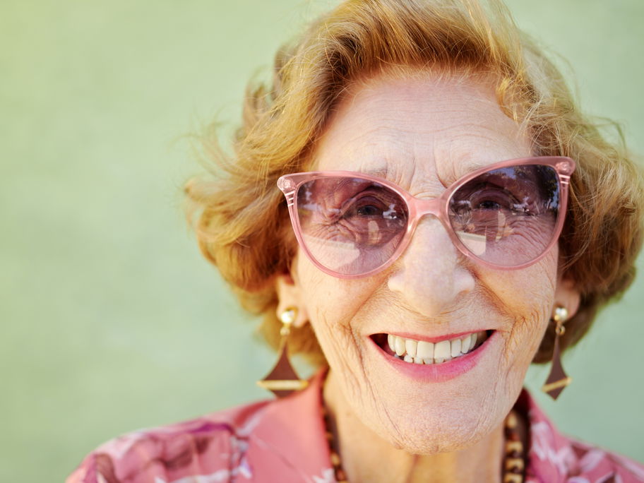 Lachende alte Frau mit rosa Sonnenbrille.