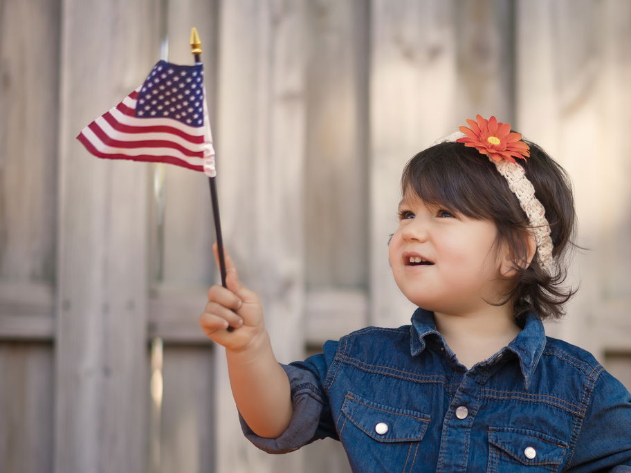 Kleines Mädchen hält eine Amerika-Flagge in der Hand.