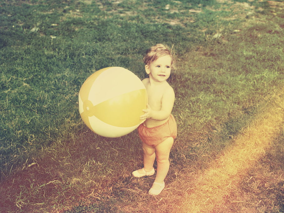 Kleinkind mit Wasserball im Garten