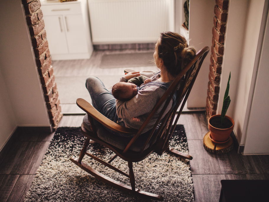 Mama stillt ihr Baby im Schaukelstuhl