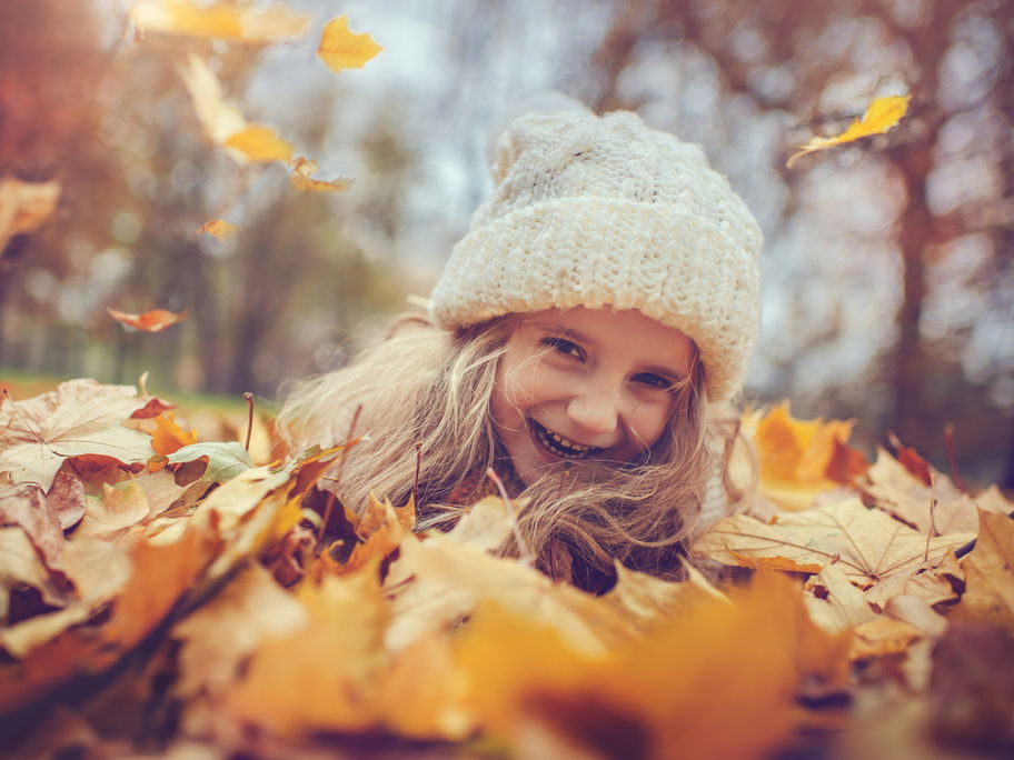 Mädchen mit Mütze im Herbstlaub.