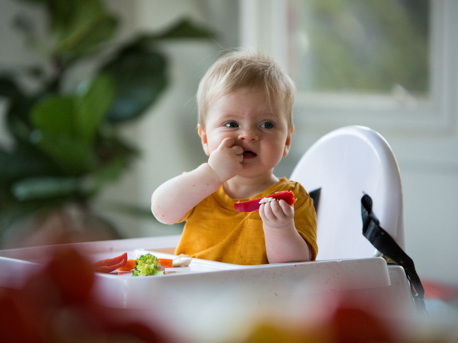 Baby sitzt in Hochstuhl mit Tisch und isst
