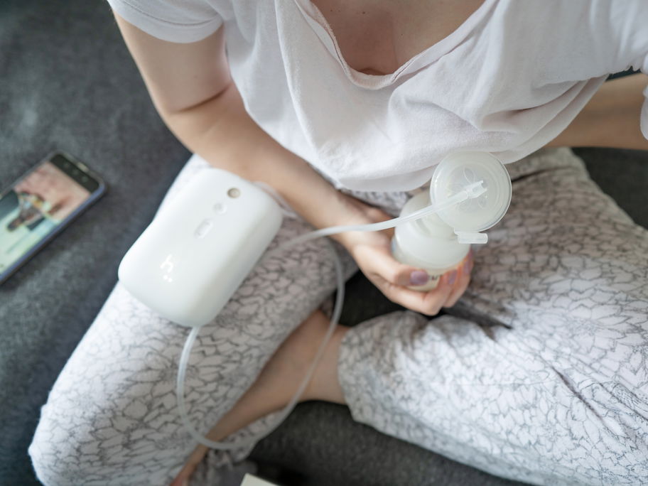 Eine Mama pumpt mit einer elektrischen Milchpumpe Muttermilch ab.