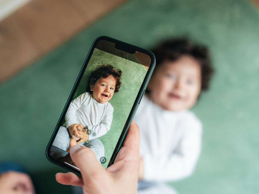 Ein Baby, das mit einem Handy fotografiert wird.