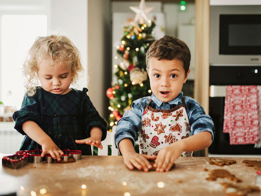 Ein Mädchen und ein Junge kneten zuckerfreien Plätzchen-Teig mit den Händen zur Weihnachtszeit.