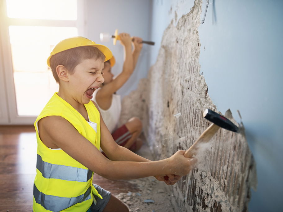 Kind spielt Bauarbeiter und zerstört eine Wand.