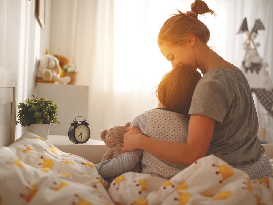 Mutter weckt ihre Tochter morgens im Bett.