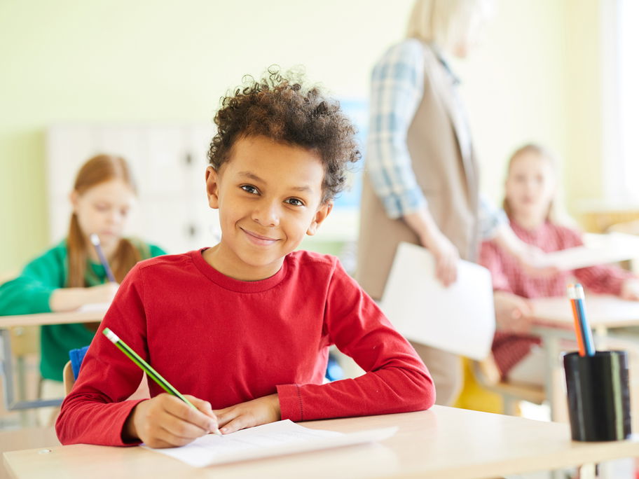 Schüler sitzt lächelnd im Klassenraum.