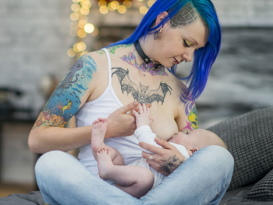 Tätowierte Frau stillt ihr Baby.