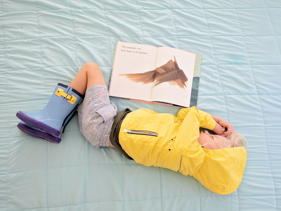 Ein Kind in Regenkleidung beim Lesen eingeschlafen