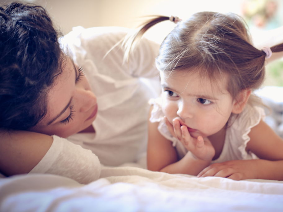 Mutter spricht mit ihrer Tochter im Bett.