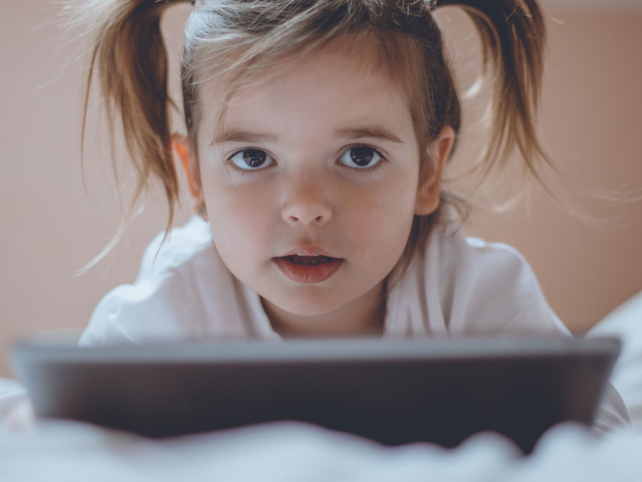 Kleines Mädchen mit Tablet im Bett.