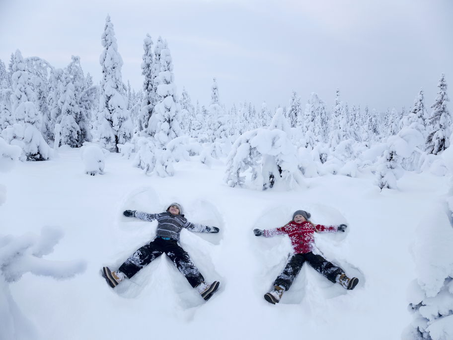Zwei Kinder machen Schneeengel.