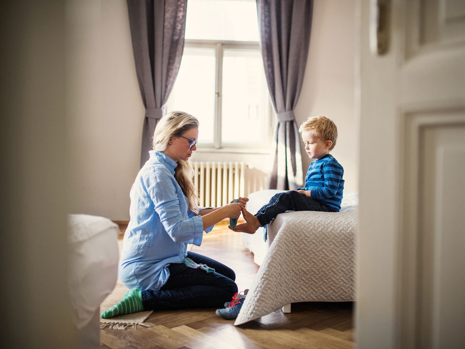 Mutter zieht ihrem Sohn die Socken an.