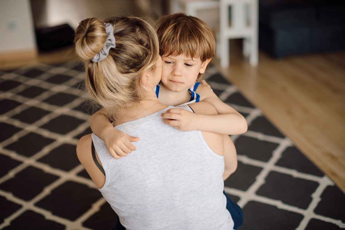 Ein kleiner Junge lässt sich von seiner Mutter in den Arm nehmen, um getröstet zu werden.