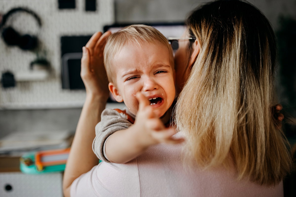 Ein kleines Kind wird bei einem Wutanfall von seiner Mama auf den Arm genommen und getröstet.