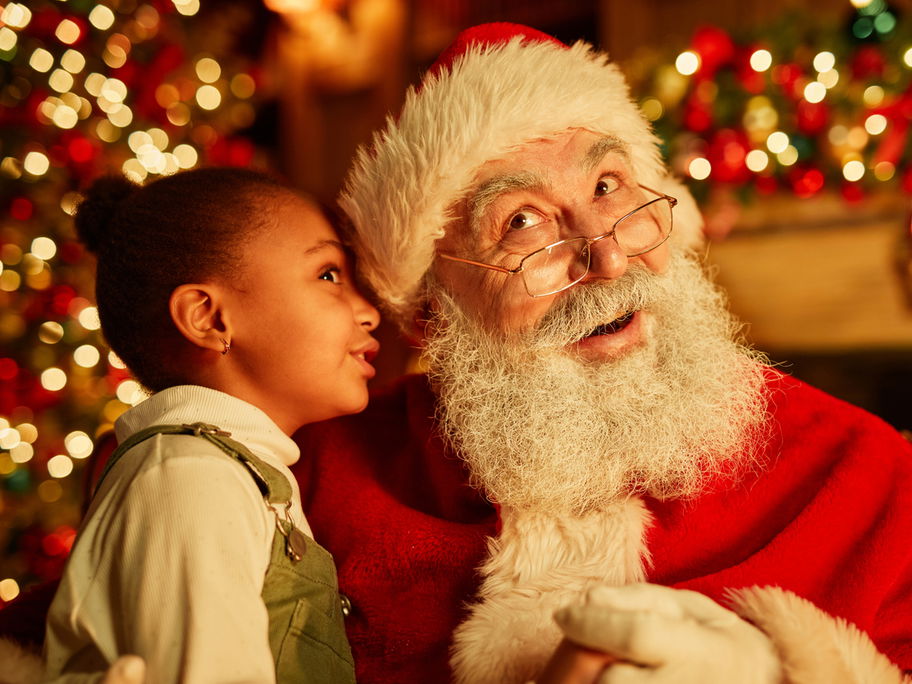 Kleines Mädchen flüstert dem Nikolaus ein Gedicht ins Ohr.